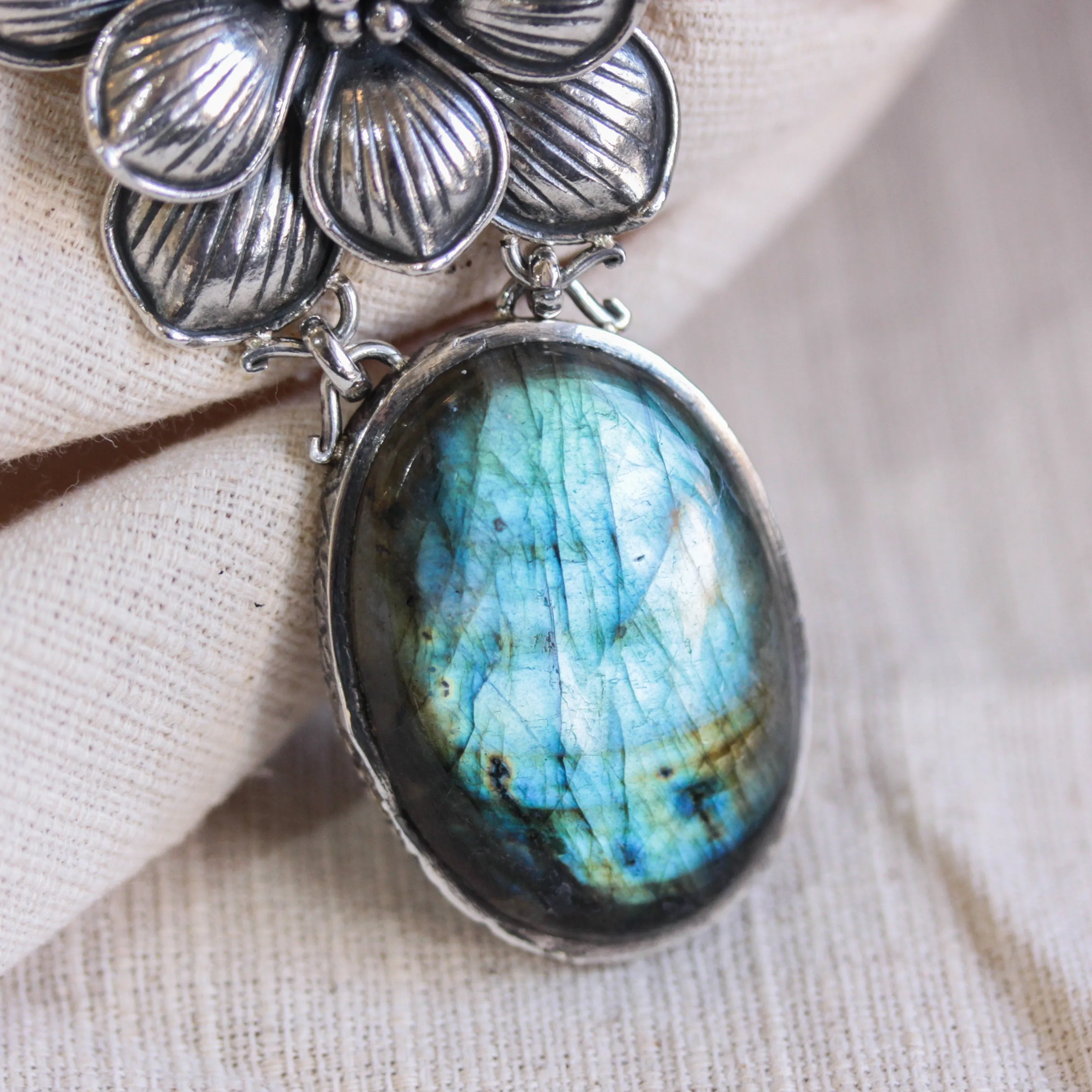 Oval Labradorite pendant necklace in silver bezel setting with silver in flower shape on silver chain