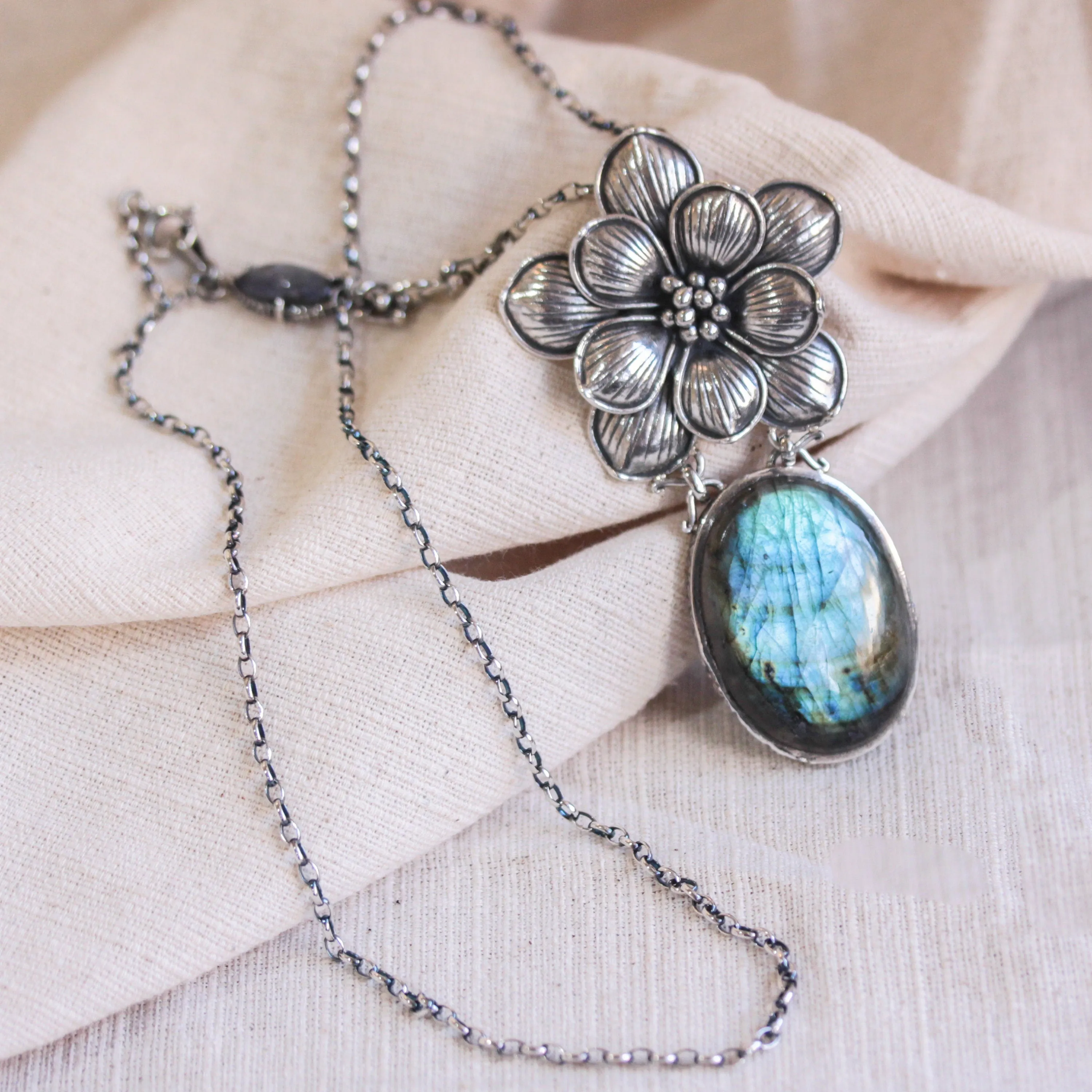 Oval Labradorite pendant necklace in silver bezel setting with silver in flower shape on silver chain